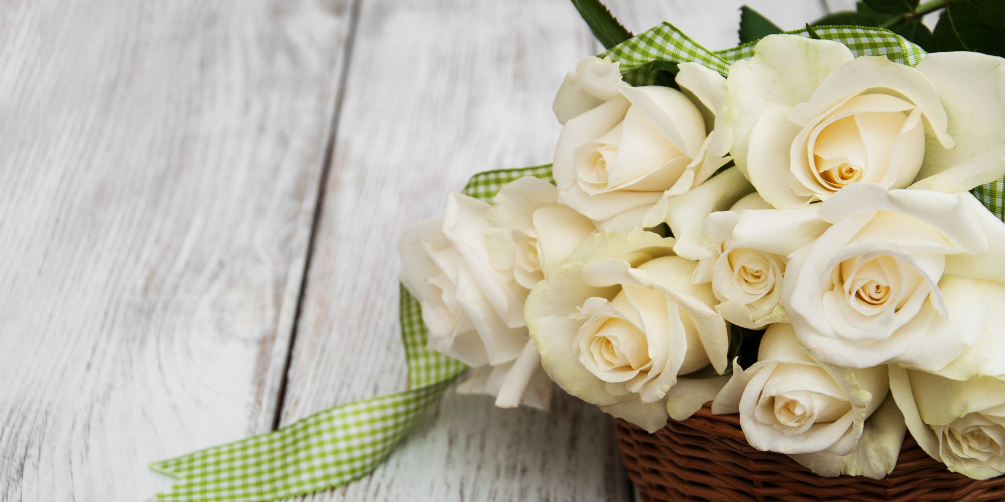 Bouquet de roses blanches artificielles posé sur une table en bois