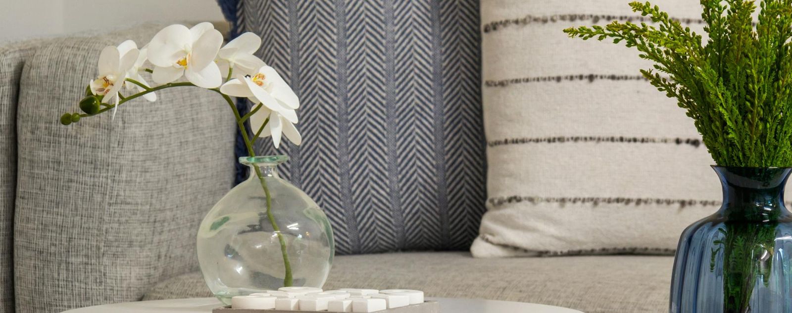 Fleurs artificielles blanches dans un vase posé sur un canapé